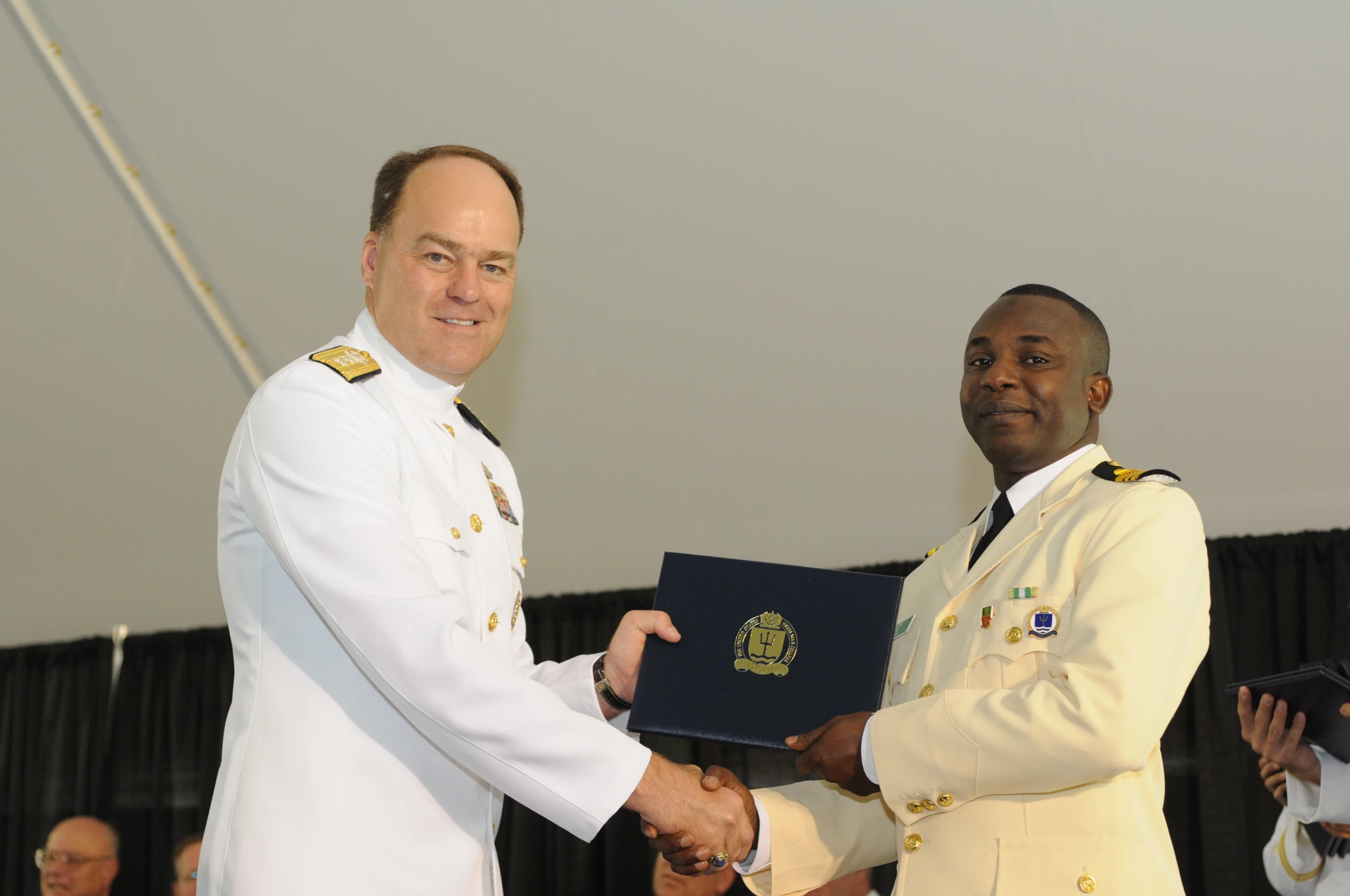 two men in uniforms are shaking hands at a ceremony