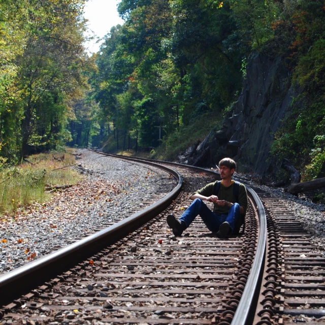 a person sitting on the end of train tracks