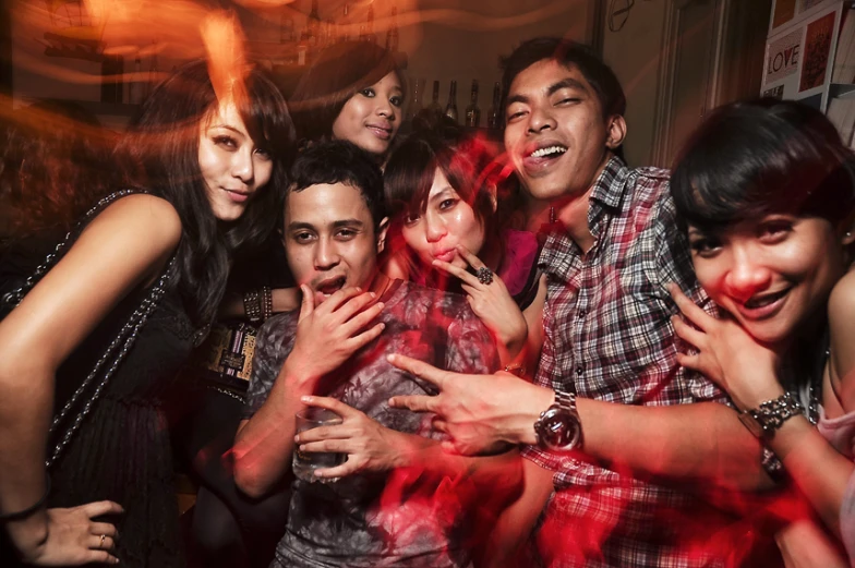 a group of young people pose for the camera with their red glow sticks in the air