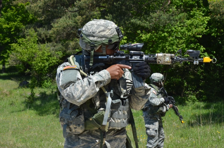 two soldiers standing next to each other while aiming at soing