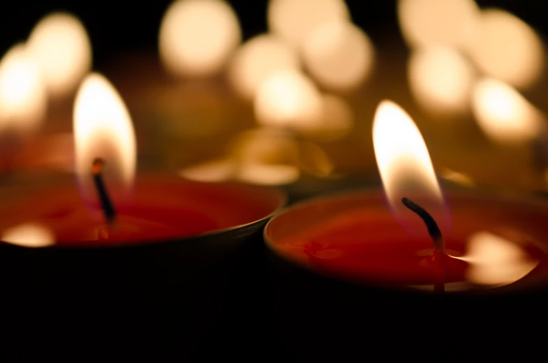 several lit candles placed in an array with white ones