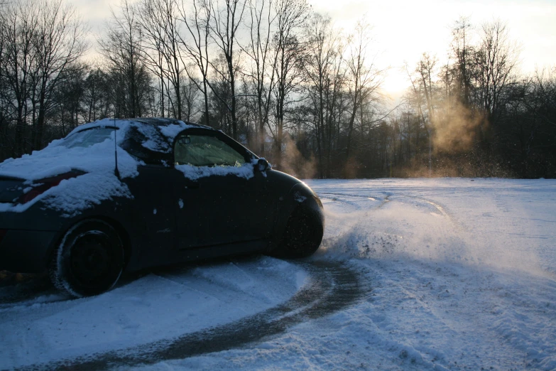 a car parked on a snowy road surrounded by wooded area