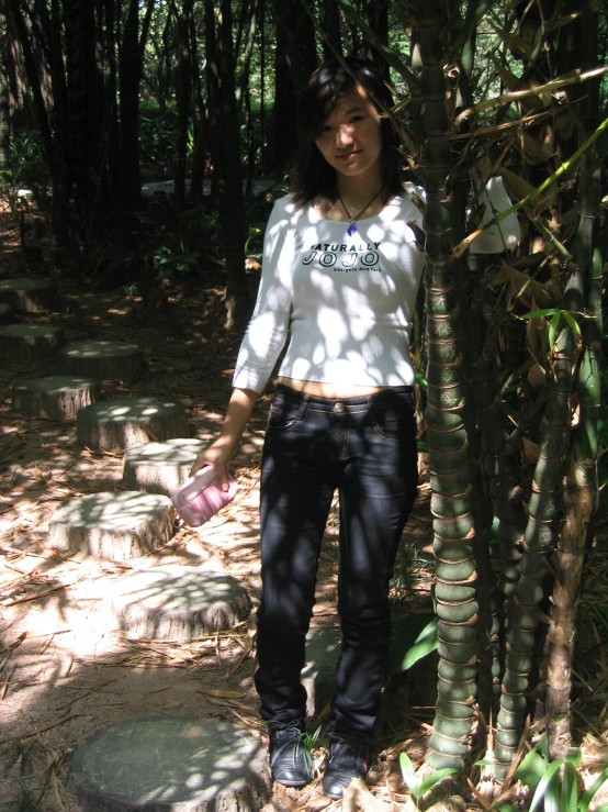 a young woman standing in the woods by some trees