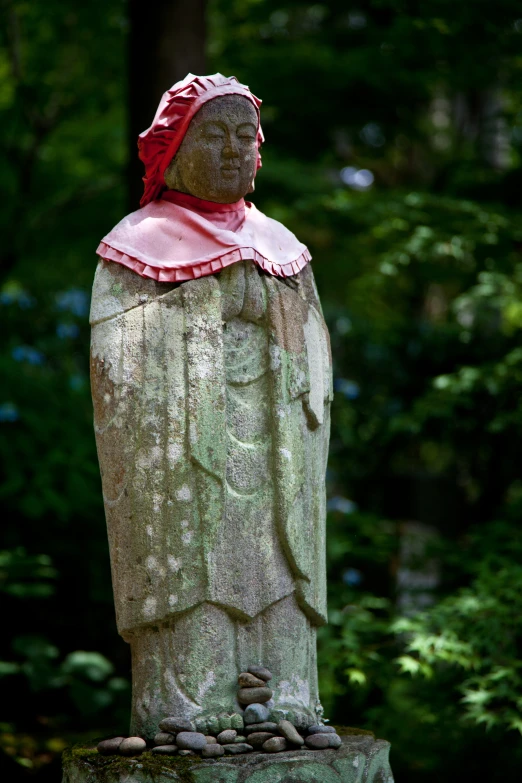 a carved statue of a lady is sitting in a park