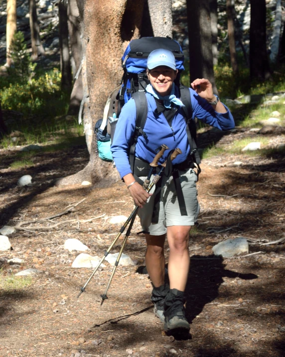 a woman hiker with a backpack and ski poles in a forest
