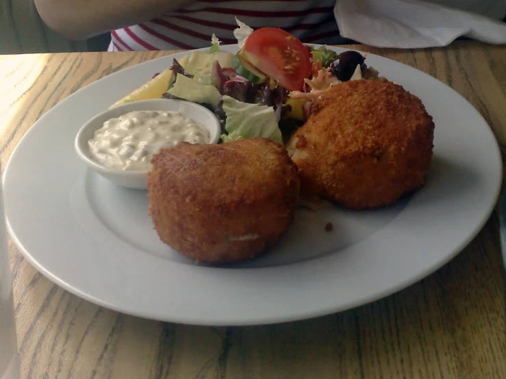 a plate with two chicken patties and salad