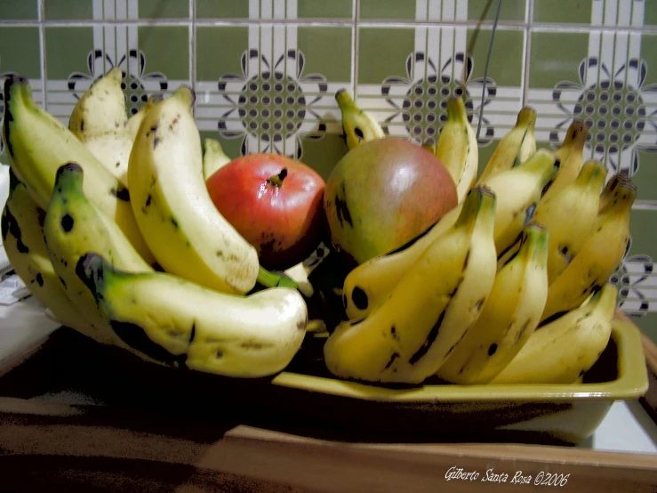 a bowl of bananas and an apple on a counter