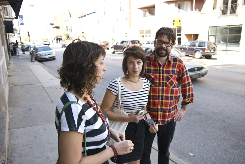 two women standing next to two men on the side of the street