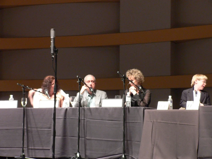 four people sitting at a table in front of microphones