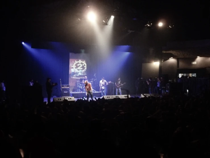 a band performing on stage at night with lights in the dark