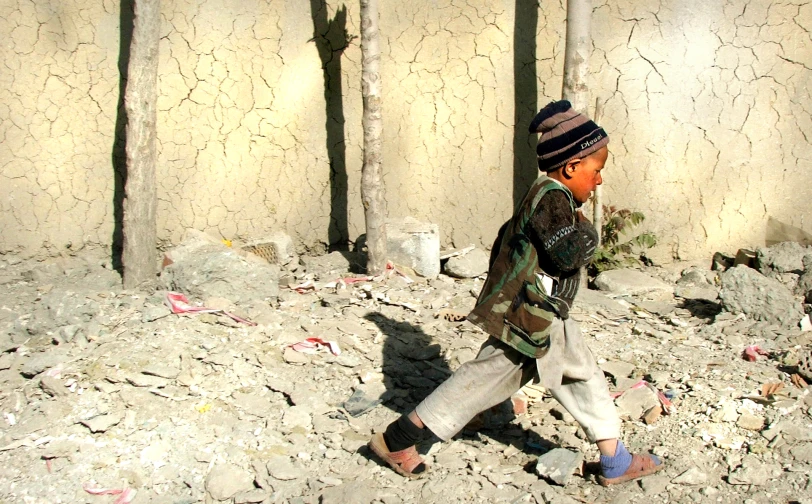 small child walking past stone wall on rock road