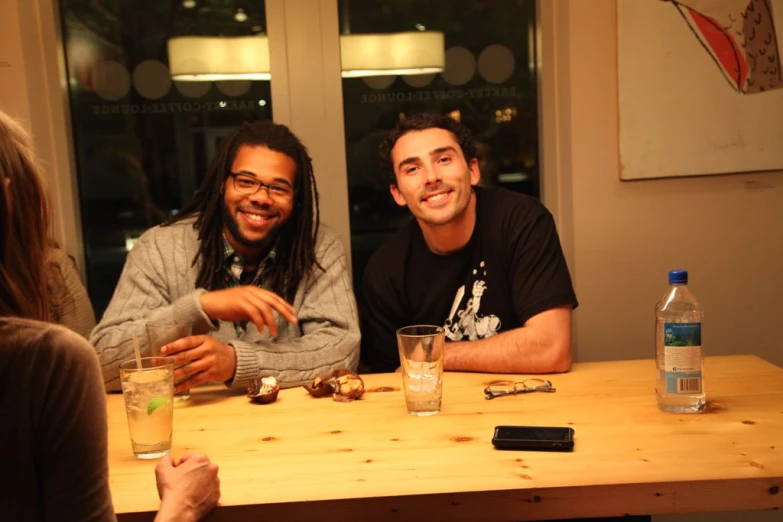 two young men sitting at a table with glasses