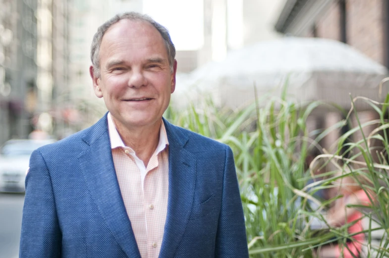 a man in a blue blazer and a pink shirt and white hat