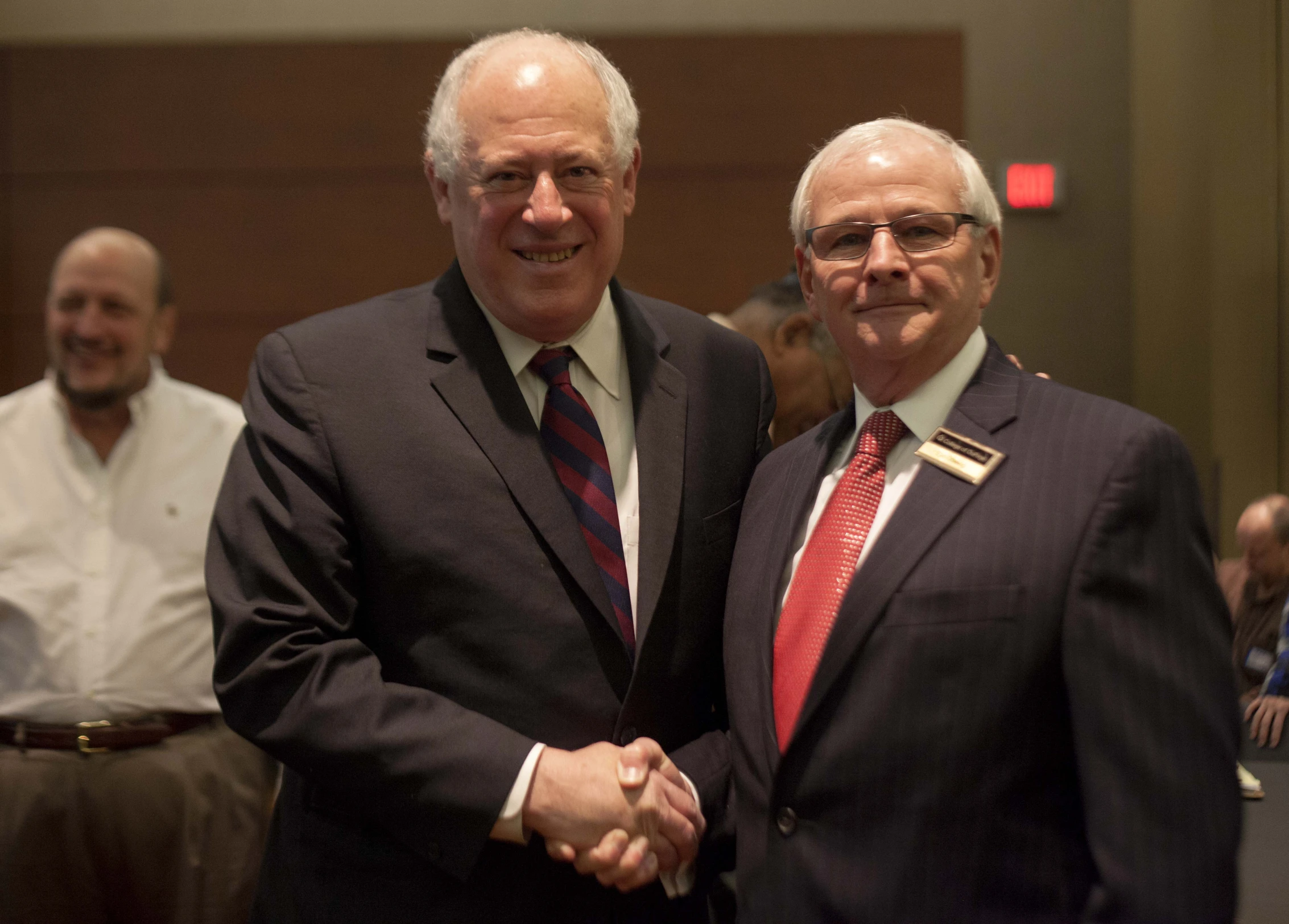 two men in business suits shaking hands at a meeting