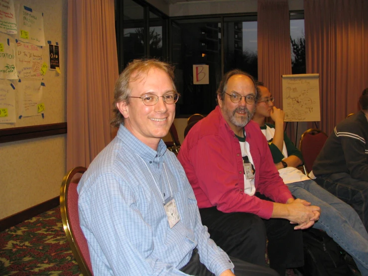 three men smile while sitting in a room