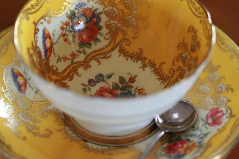 a yellow china tea set, with a saucer and cups on the side, with spoons resting in the top