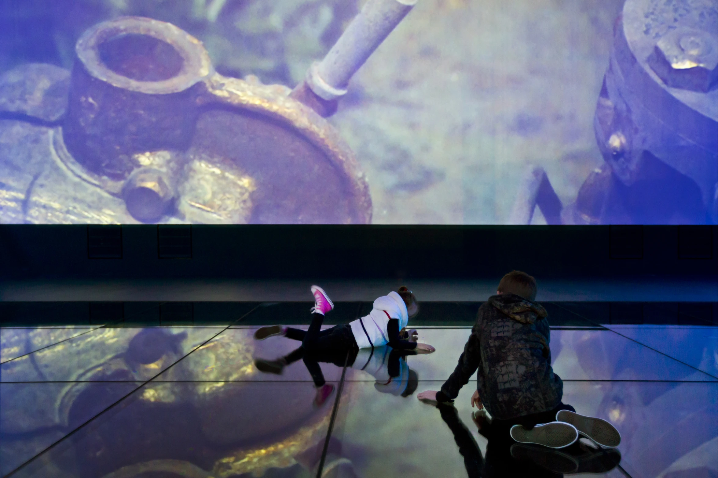 people walking past a huge projection of an industrial machine