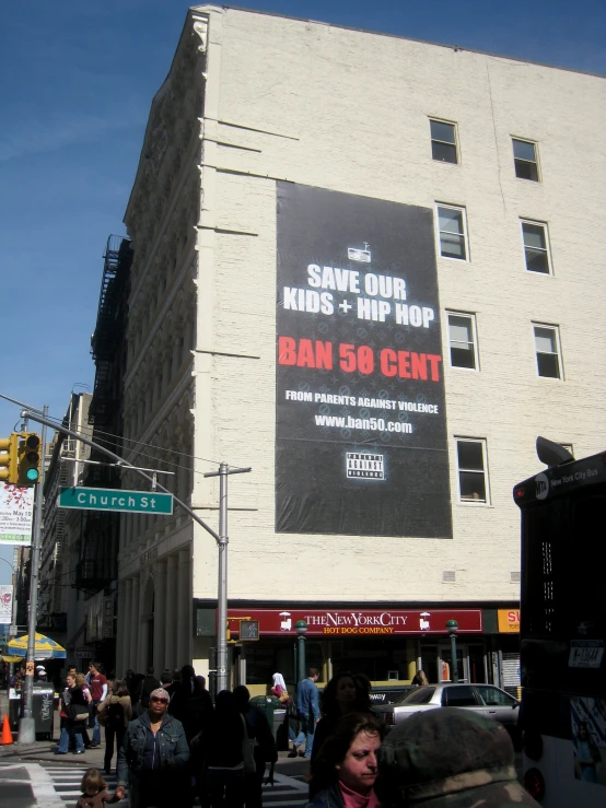 people standing outside of a building with an advertising sign