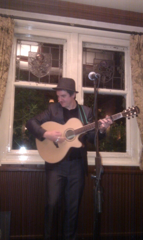 a man in a suit plays guitar by the window