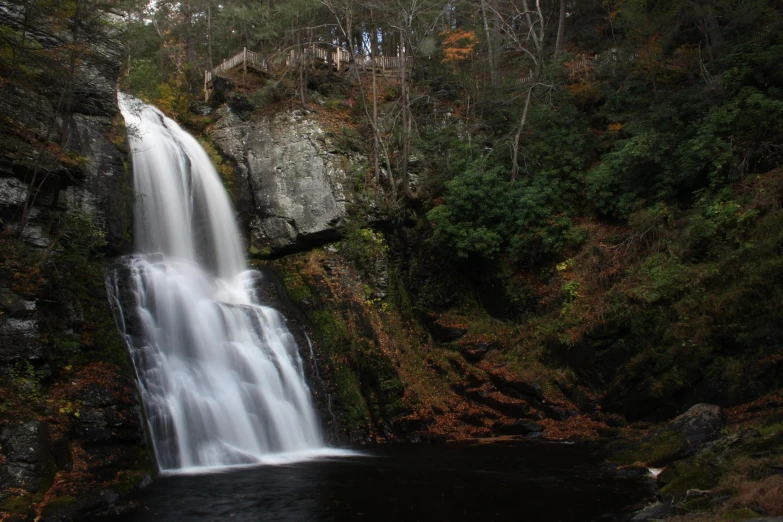 a waterfall on a river in front of trees