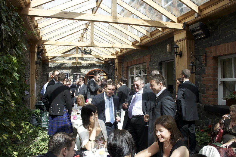 people dressed up for a wedding reception are socializing outside