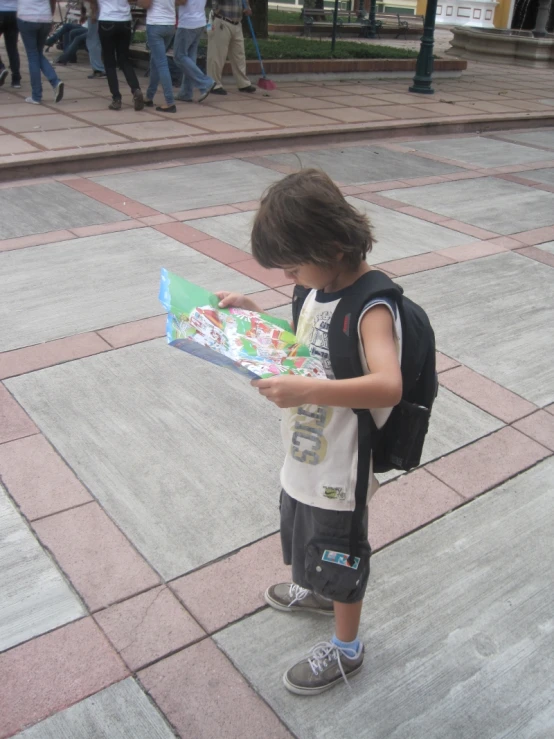 a  standing on the sidewalk looking at his book