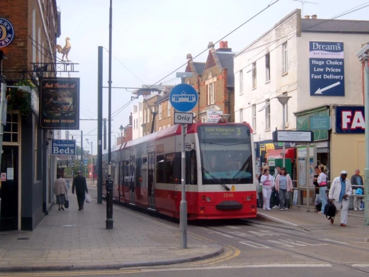 a red and white bus traveling down a street next to buildings