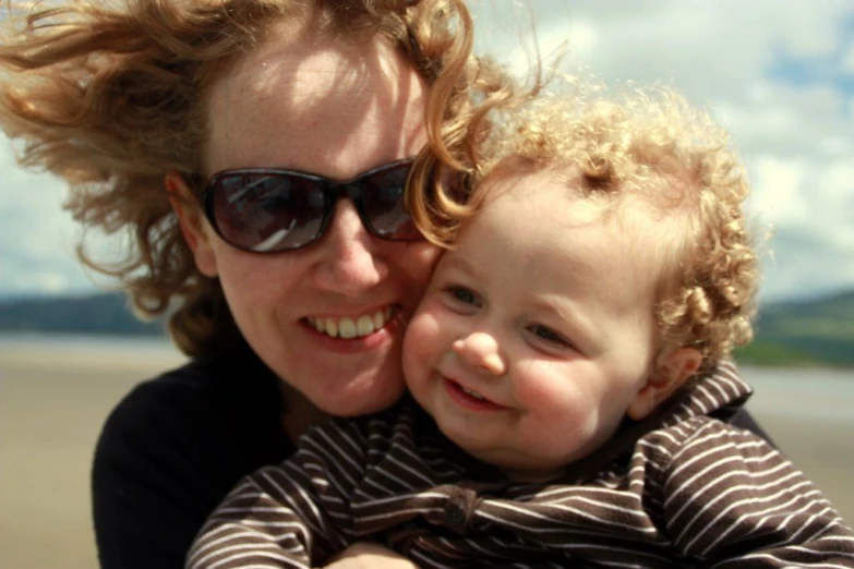 mother and child together at the beach with a sky in background