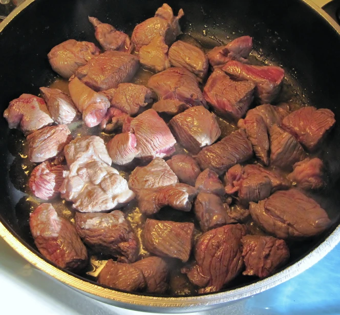 meat cooking in a pan on the stove