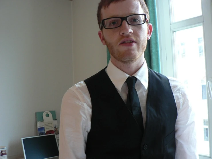 man wearing glasses and a black vest and tie