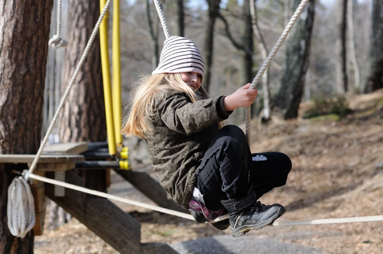 a small child swinging on ropes in the forest