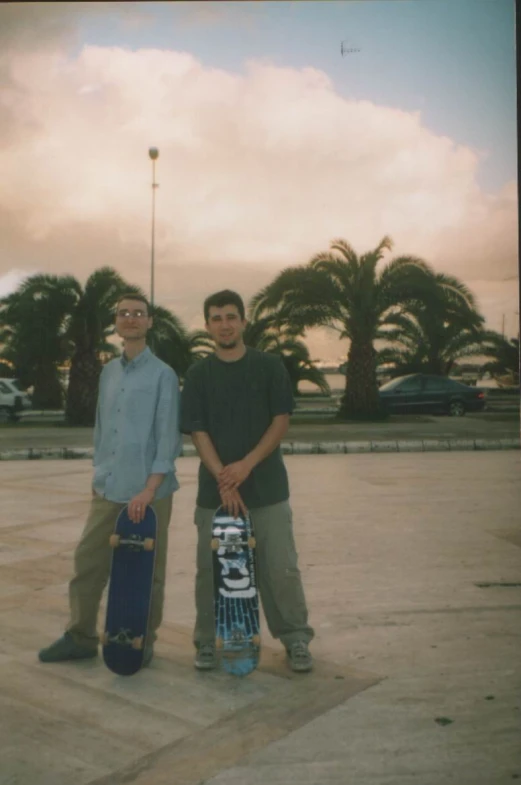 two men pose with skateboards on the concrete