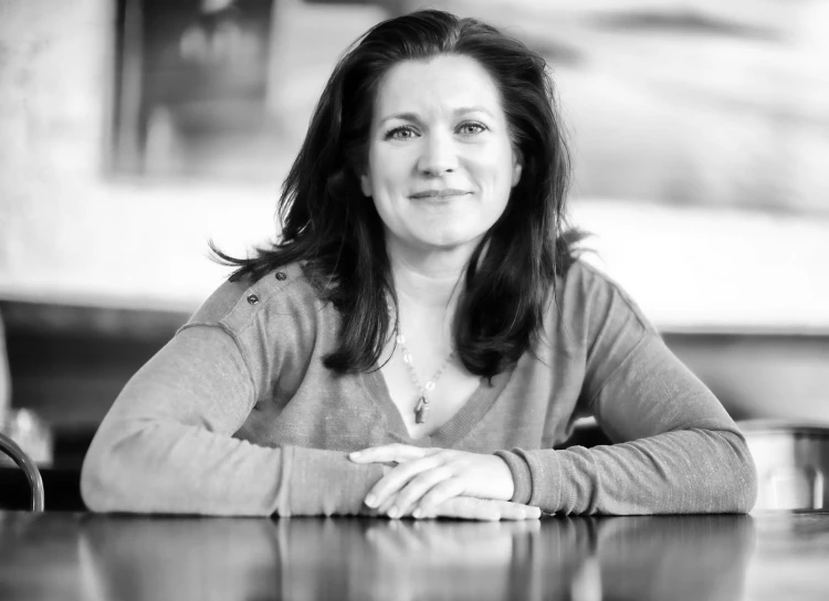 black and white pograph of a woman sitting at a wooden table