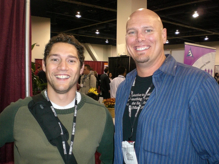 two men smiling for the camera in an indoor event