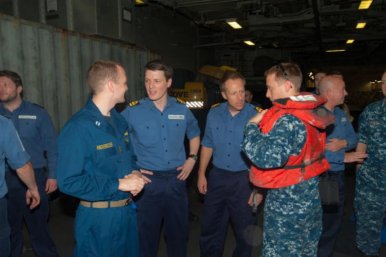 four soldiers stand by an airplane talking to some men in uniforms