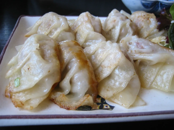 an assortment of dumplings with sauce and vegetables