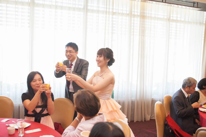 two asian people in formal attire stand by a banquet table