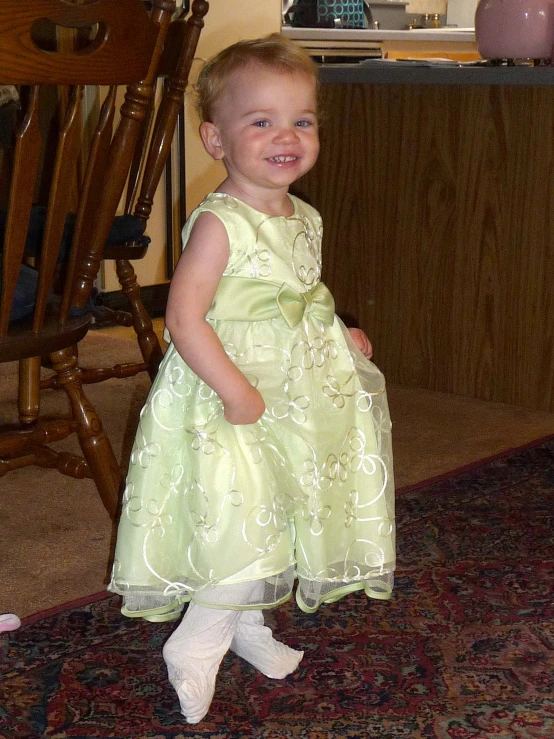 little girl smiling wearing green dress near red carpet