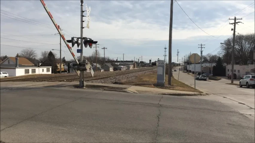 railroad tracks with traffic lights suspended above them and cars on the street below