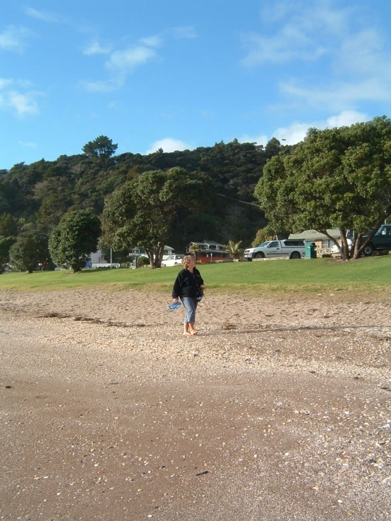 there is a man walking across a field with a kite