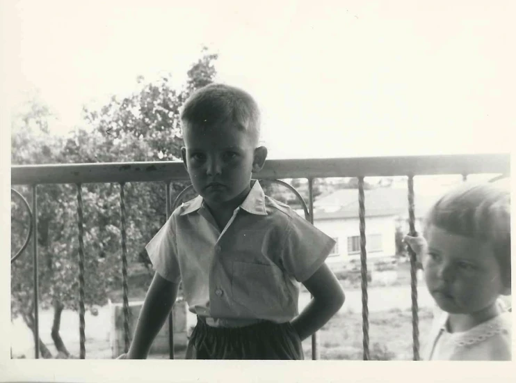 two children standing near each other outside near a fence