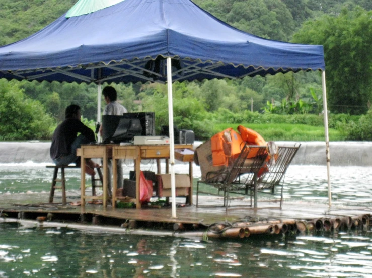 people on a dock on the water under a tent