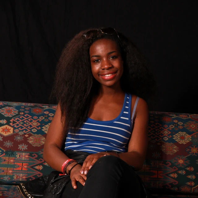 a young woman in blue and white shirt sitting on couch