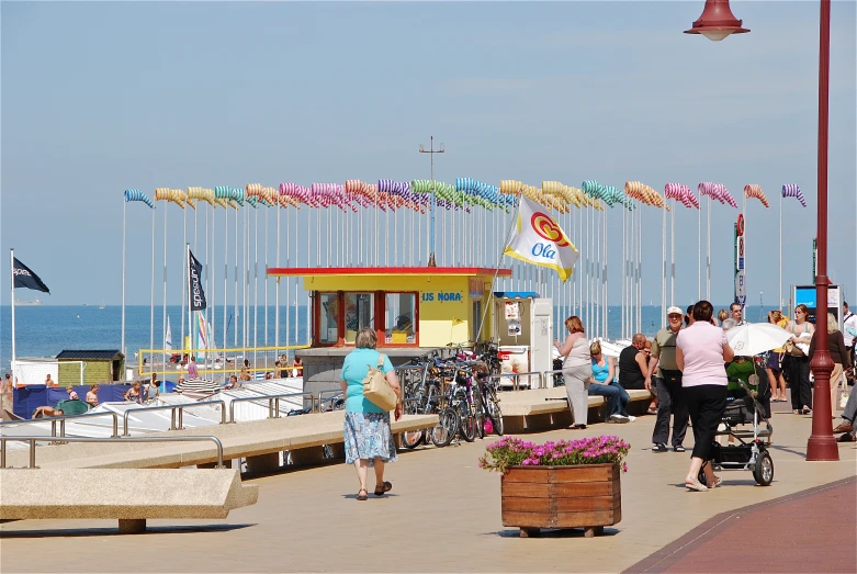 many people are walking on the sidewalk near the water