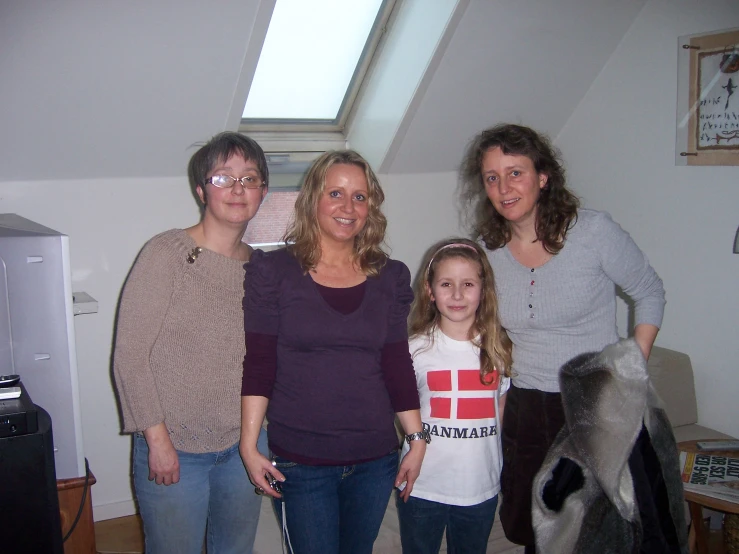 three women and a child are standing near a couch