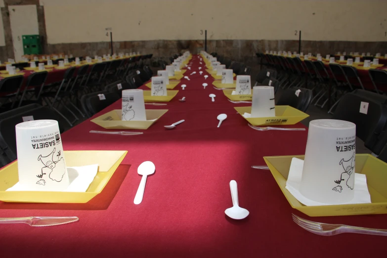 a long red table has been set with place mats and napkins