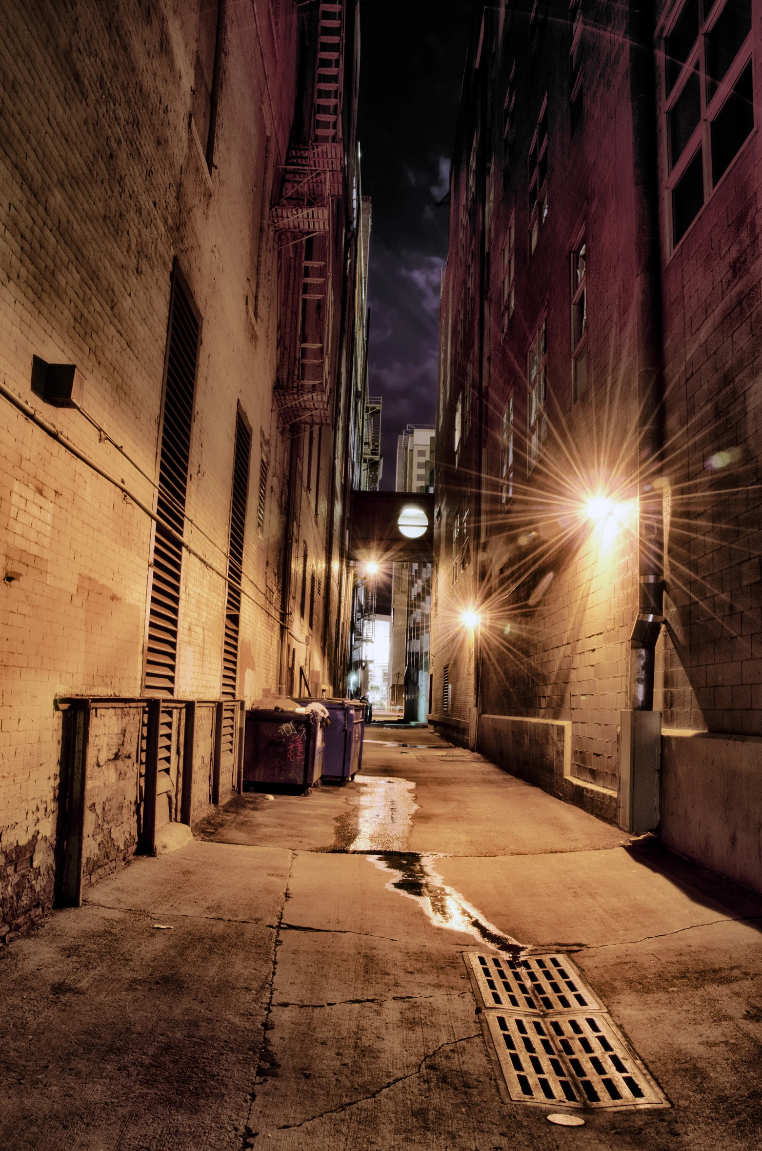 a narrow, dark alley at night with the street lights on