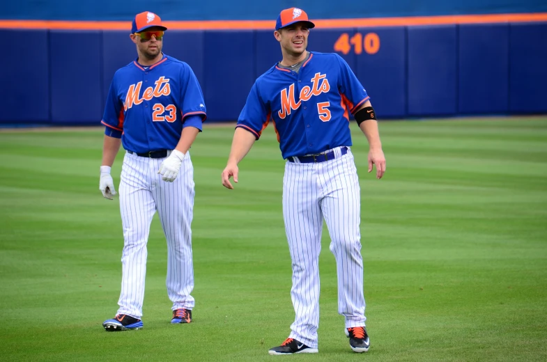 two professional baseball players stand together on the field