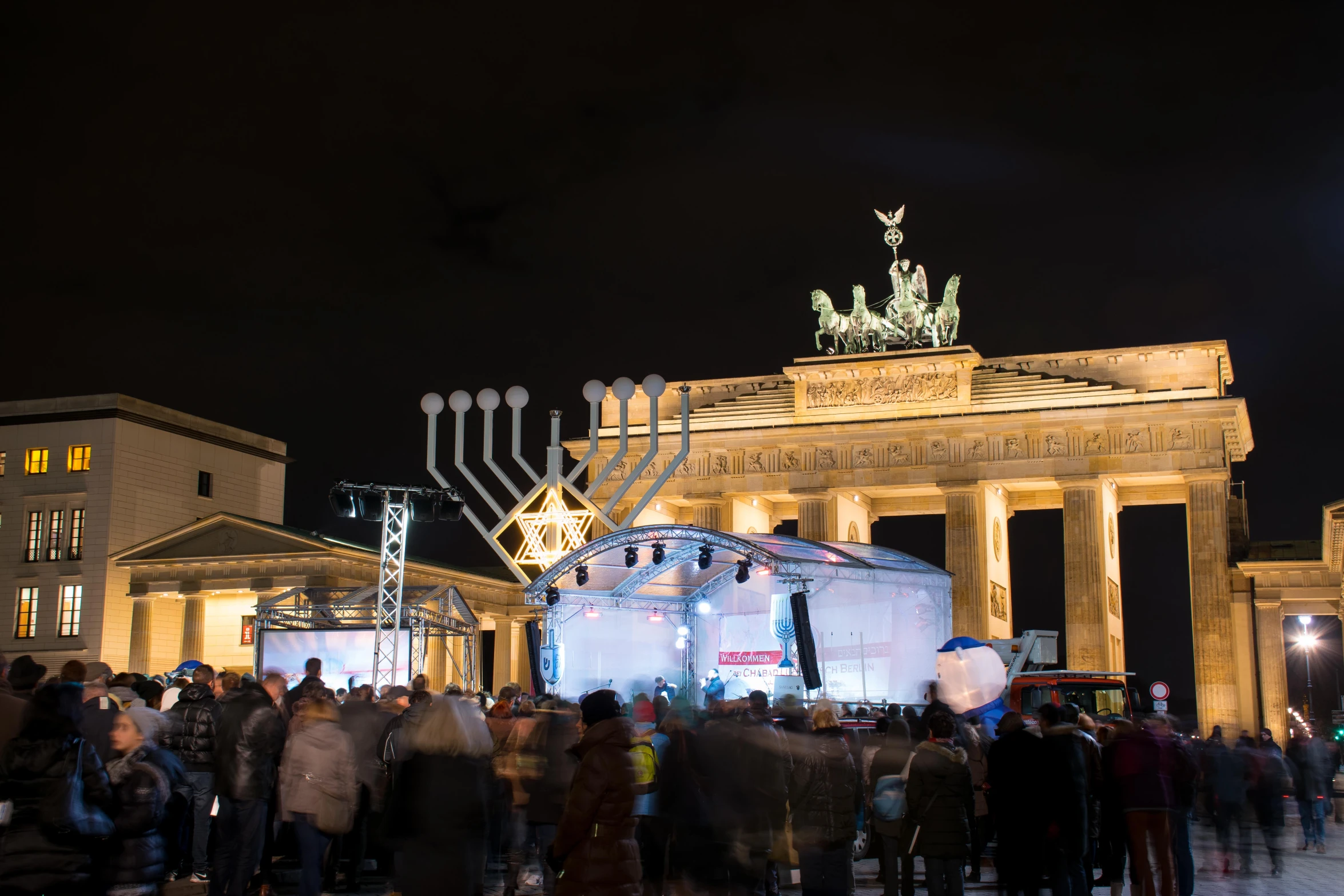 a huge crowd stands outside a building in front of the monument