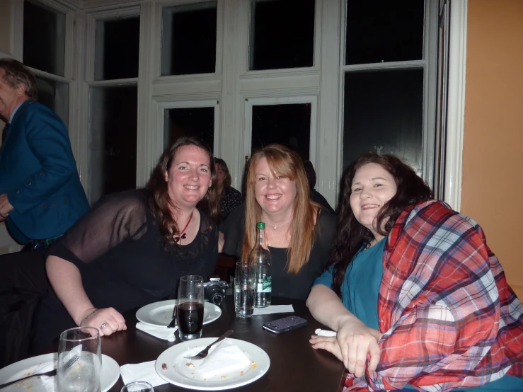 four women are sitting at a table posing for the camera